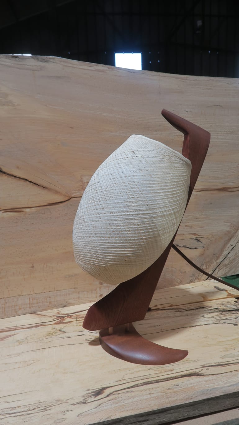 Lampe sculptée en bois posée sur un plateau massif